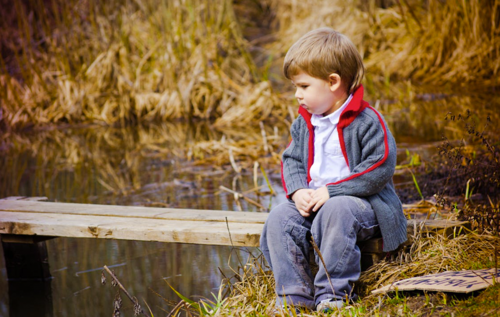 enfant qui réfléchit au bord de l'eau